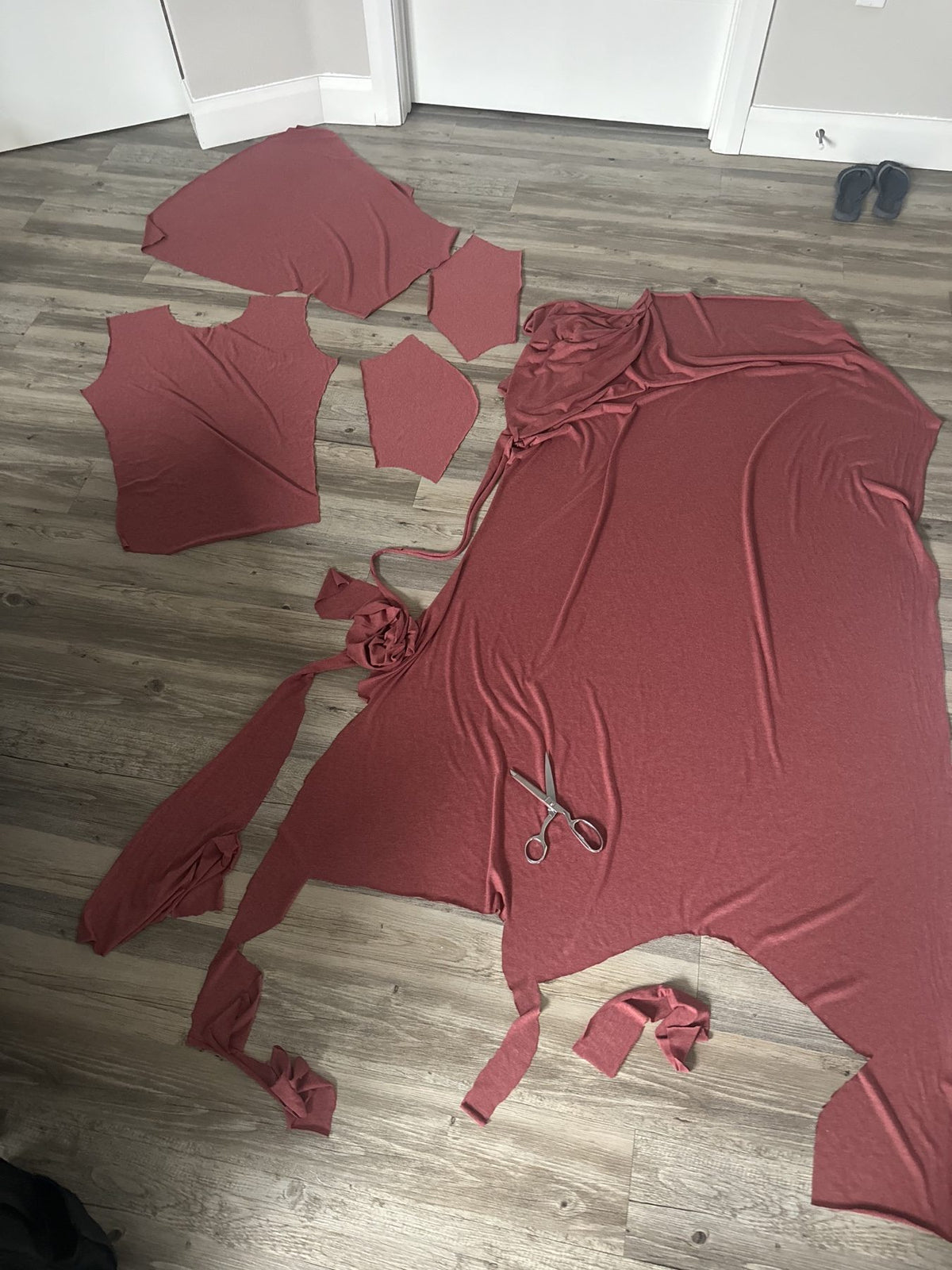 Burgundy fabric cut into garment pieces with scissors beside them