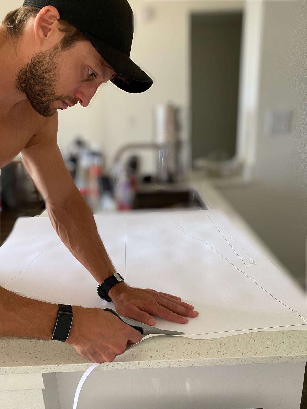 Cutting a paper garment pattern by hand on a kitchen counter